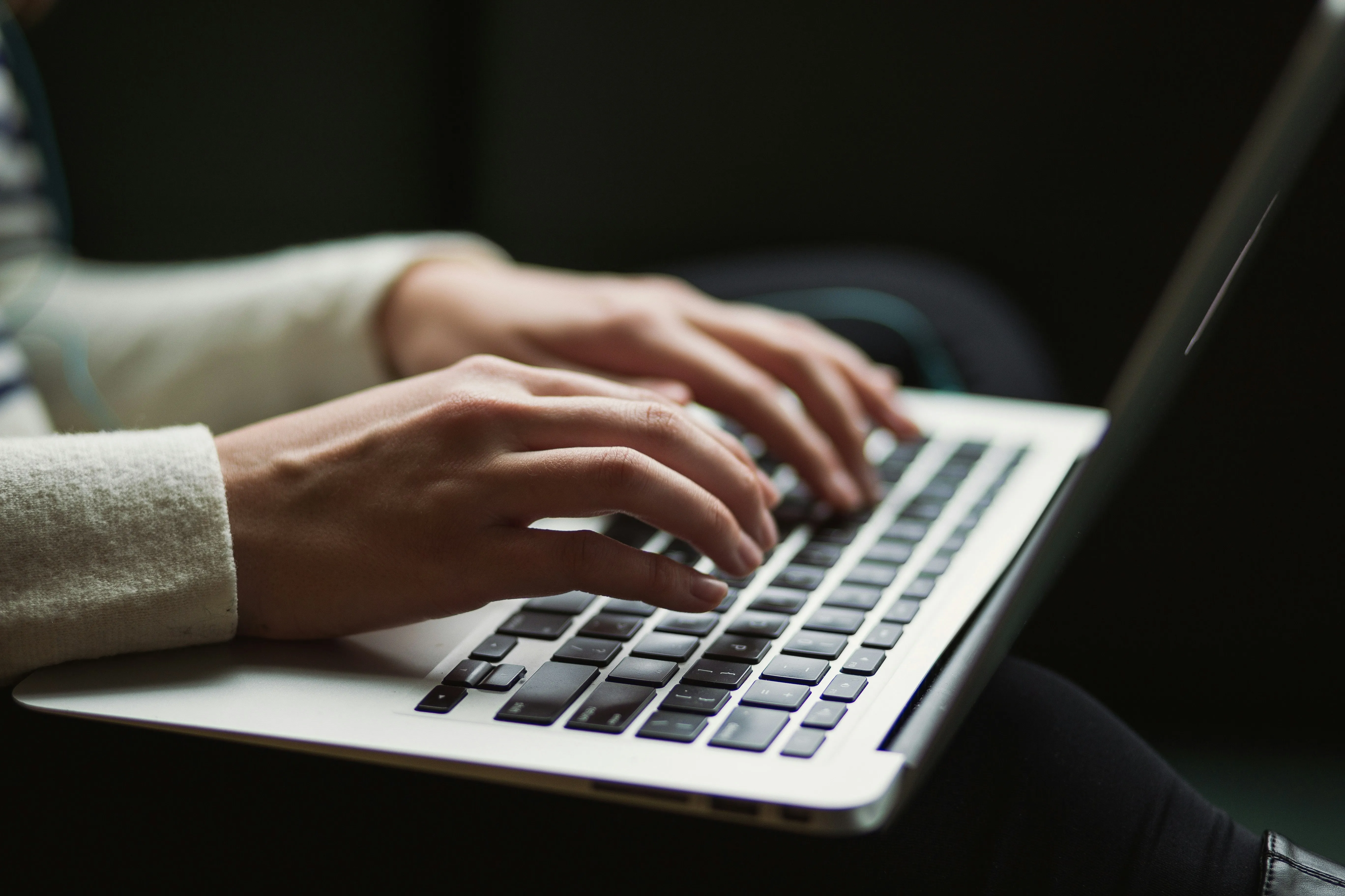 A person's hands typing on a laptop.